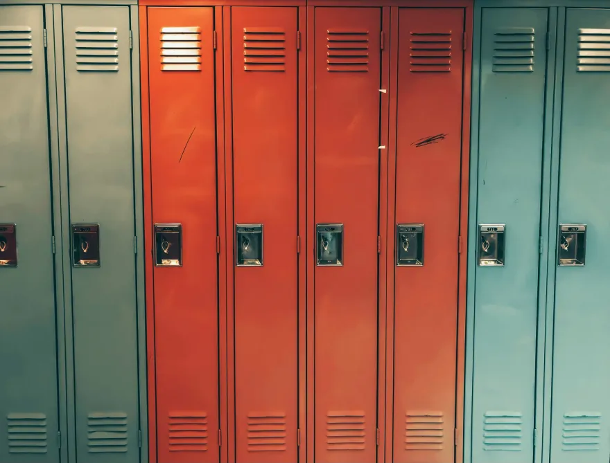 A row of school lockers, bright orange in the middle with pale teal on either side