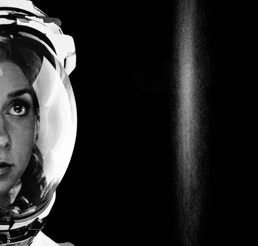 Lauren Lapkus in a spacesuit helmet, looking upward, in a still from Unbound